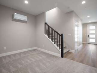 Step into this modern home featuring a spacious living area with plush carpeting and a convenient split AC unit for year-round comfort.
