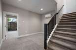 This spacious interior features a modern staircase with dark wood railings and plush carpeting, leading to the upper level.