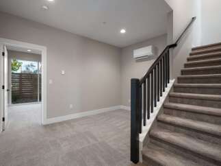 This spacious interior features a modern staircase with dark wood railings and plush carpeting, leading to the upper level.