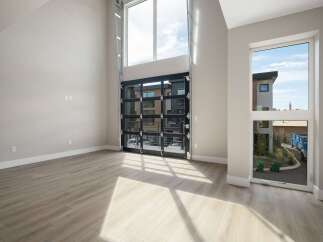 Experience modern living in this spacious room featuring a dramatic floor-to-ceiling glass garage door that opens to the outdoors.