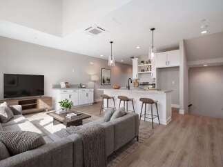 Experience modern living in this open-concept condo featuring a sleek kitchen with a breakfast bar and pendant lighting, perfect for entertaining.