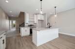 Discover modern living in this stunning kitchen featuring sleek white cabinetry, a spacious island with a contemporary faucet, and elegant pendant lighting.