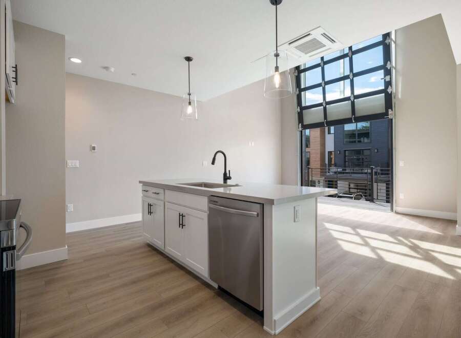 Experience modern living in this stunning apartment featuring a sleek kitchen island with a built-in sink and dishwasher.
