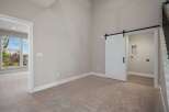 Discover modern living with this spacious room featuring a stylish white barn door leading to a convenient laundry area.