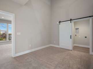 Discover modern living with this spacious room featuring a stylish white barn door leading to a convenient laundry area.
