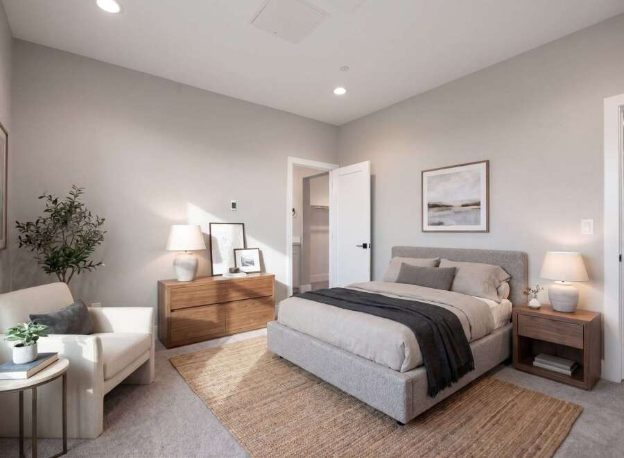 Discover this inviting bedroom featuring a plush king-sized bed adorned with a charcoal throw, complemented by a cozy armchair and a natural jute rug.