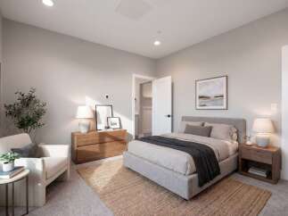 Discover this inviting bedroom featuring a plush king-sized bed adorned with a charcoal throw, complemented by a cozy armchair and a natural jute rug.