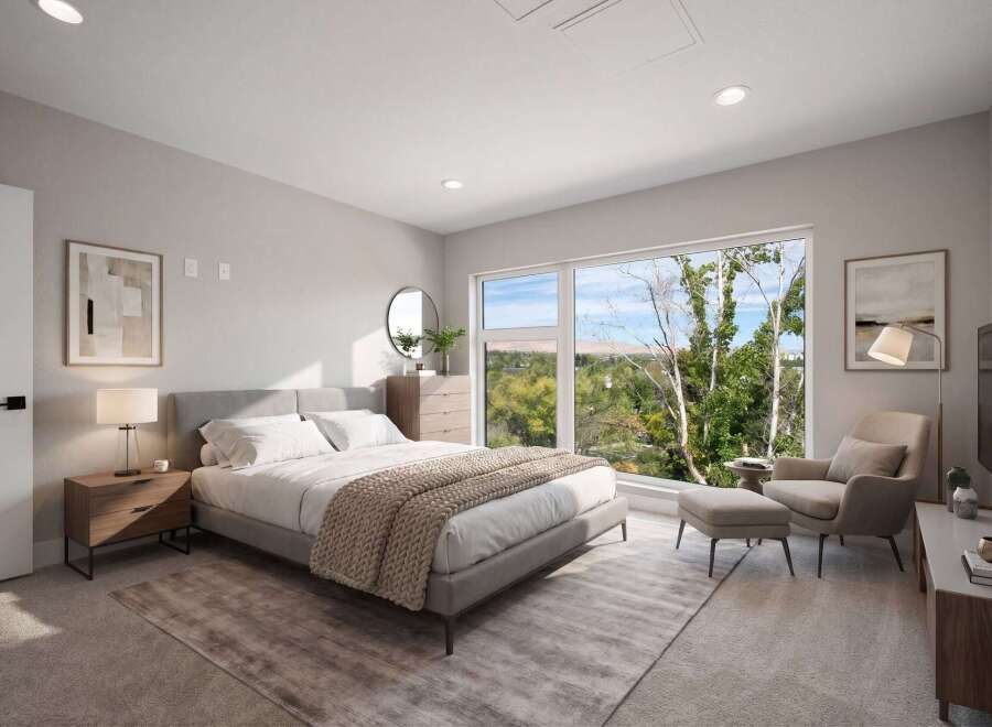 Experience modern comfort in this beautifully staged bedroom, featuring a plush king-sized bed and a cozy reading nook with an armchair and ottoman.