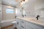 This modern bathroom features a sleek white vanity with dual sinks and black fixtures, complemented by a spacious bathtub and toilet.