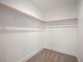 This spacious walk-in closet offers ample storage with its extensive shelving and hanging rods.