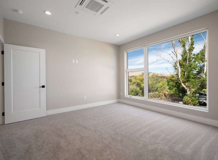 Experience modern living in this spacious room featuring a large picture window that floods the space with natural light and offers stunning views of the surrounding greenery.