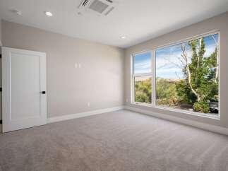 Experience modern living in this spacious room featuring a large picture window that floods the space with natural light and offers stunning views of the surrounding greenery.