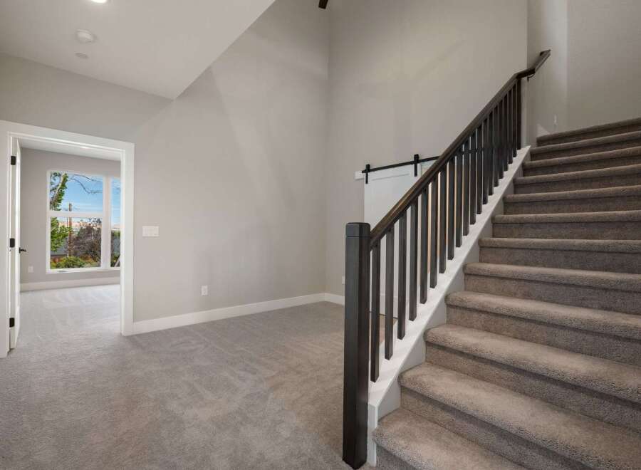 Step into this inviting home featuring a grand staircase with dark wood railings and plush carpeting.