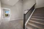 Step into this inviting home featuring a grand staircase with dark wood railings and plush carpeting.