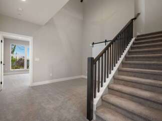Step into this inviting home featuring a grand staircase with dark wood railings and plush carpeting.