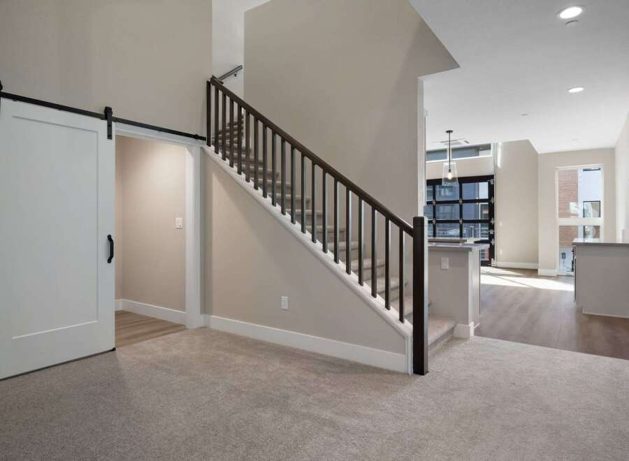 Experience modern living in this stunning home featuring a sleek barn door leading to a private space and a beautifully carpeted staircase with dark wood railings.