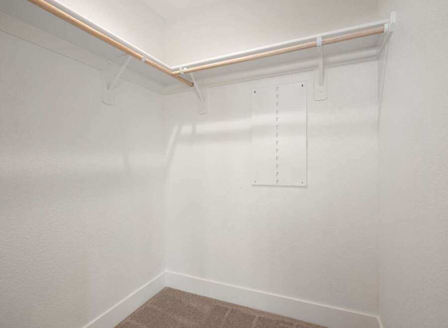 This spacious walk-in closet offers ample storage with dual-level hanging rods, perfect for organizing your wardrobe.