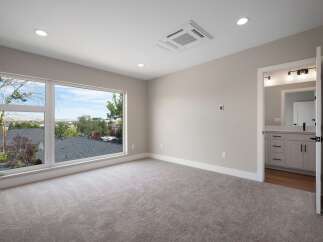 Experience breathtaking views from this spacious bedroom, featuring a large picture window that floods the room with natural light.