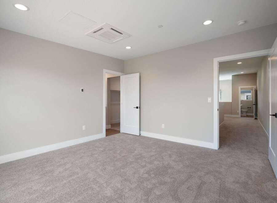 Step into this spacious bedroom featuring plush carpeting and neutral-toned walls, creating a serene atmosphere.