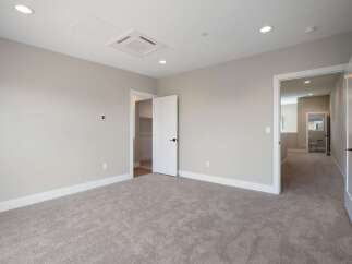 Step into this spacious bedroom featuring plush carpeting and neutral-toned walls, creating a serene atmosphere.