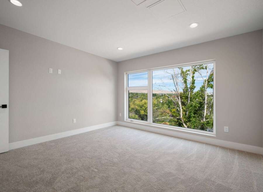 Experience modern living in this spacious bedroom featuring plush carpeting and a large, picturesque window that floods the room with natural light.
