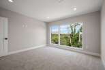 Experience modern living in this spacious bedroom featuring plush carpeting and a large, picturesque window that floods the room with natural light.