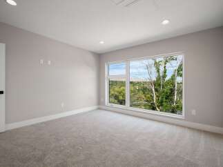 Experience modern living in this spacious bedroom featuring plush carpeting and a large, picturesque window that floods the room with natural light.