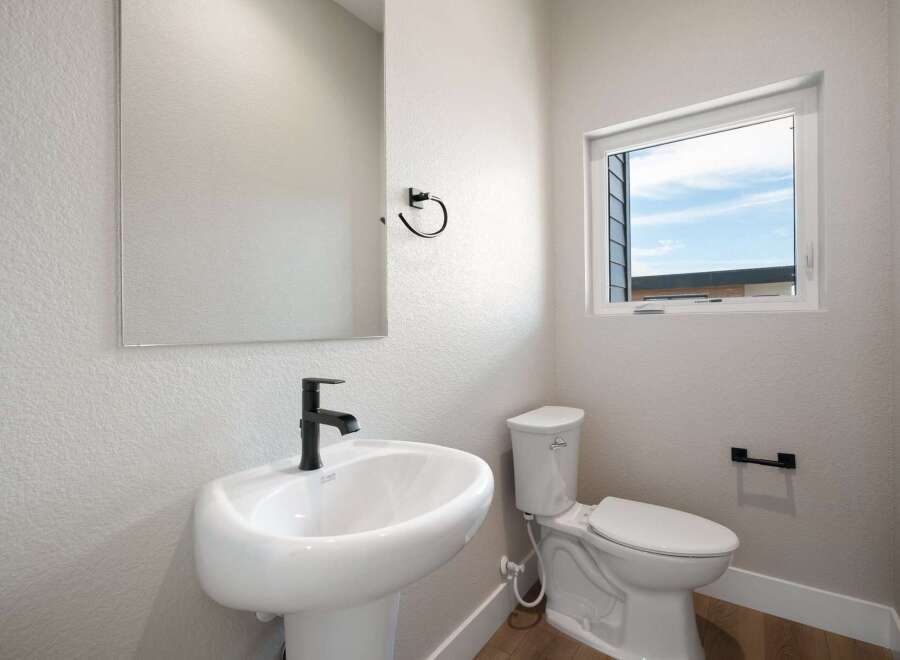 This modern bathroom features a sleek pedestal sink with a black faucet, complemented by a matching towel ring.
