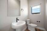 This modern bathroom features a sleek pedestal sink with a black faucet, complemented by a matching towel ring.