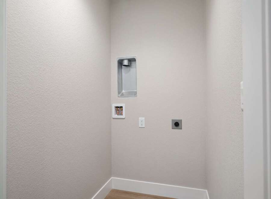 This laundry room is equipped with essential hookups for your washer and dryer, including a dryer vent and water connections.