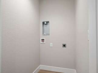 This laundry room is equipped with essential hookups for your washer and dryer, including a dryer vent and water connections.