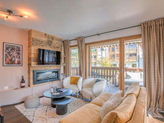 Experience cozy mountain living in this charming living room featuring a rustic wood-paneled fireplace and a modern entertainment center.