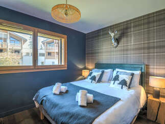 Experience cozy mountain living in this charming bedroom featuring a plush bed adorned with decorative pillows and a soft throw.