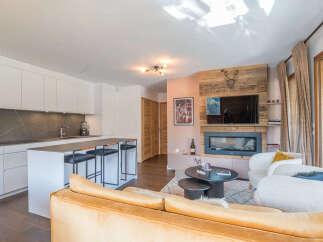 Experience modern alpine living in this stunning open-plan space, featuring a sleek white kitchen with a marble backsplash and a spacious island with bar seating.