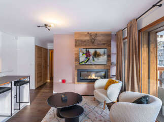 Experience cozy living in this modern apartment featuring a stylish fireplace with a mounted TV and a rustic wood accent wall.