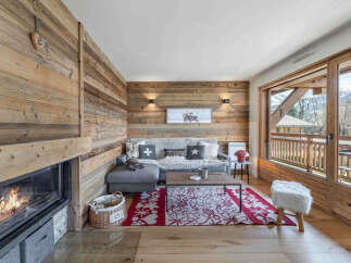 Experience cozy mountain living in this charming living room featuring a crackling fireplace and rustic wood-paneled walls.