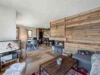 Experience cozy mountain living in this beautifully appointed living space, featuring a stunning wood-paneled wall and a modern fireplace that creates a warm ambiance.