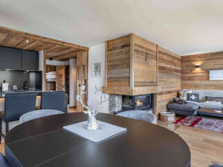 Experience rustic luxury in this stunning mountain retreat, featuring a modern kitchen with dark cabinetry and a cozy living area centered around a stone fireplace.