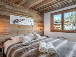 Experience rustic charm in this cozy bedroom, featuring a plush bed adorned with soft blankets and decorative pillows.