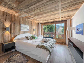Experience rustic luxury in this charming mountain bedroom, featuring a cozy bed adorned with plush pillows and a warm throw.