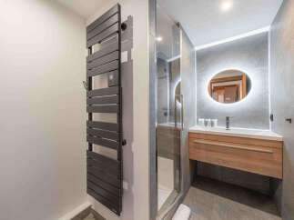 Experience modern luxury in this stunning bathroom featuring a sleek, dark gray heated towel rack.