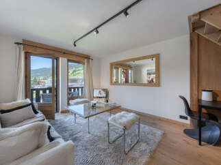 Experience mountain living in this charming apartment, featuring a spacious living area with a cozy sofa and a glass coffee table perfect for relaxing after a day of skiing.