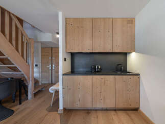 Discover this charming apartment featuring a modern kitchenette with light wood cabinetry and a sleek black countertop.