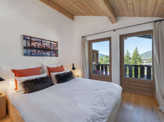 Experience mountain living in this charming bedroom featuring a comfortable bed adorned with plush pillows and a striking piece of art.