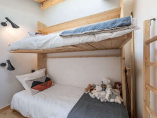 This charming bedroom features a space-saving bunk bed with natural wood accents, perfect for maximizing room capacity.
