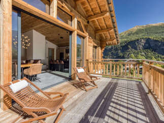 Experience luxury mountain living on this stunning wooden balcony, offering breathtaking views of the surrounding alpine landscape.