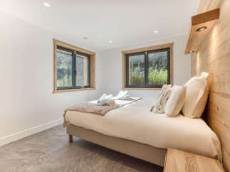 Experience serene mountain living in this charming bedroom, featuring two large windows that offer picturesque views of the surrounding greenery.