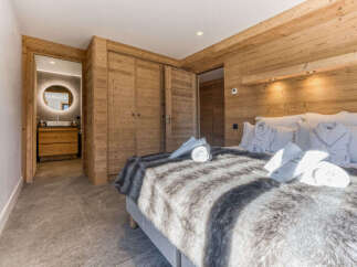 Experience luxury mountain living in this beautifully appointed bedroom featuring natural wood paneling and a plush, faux-fur throw.
