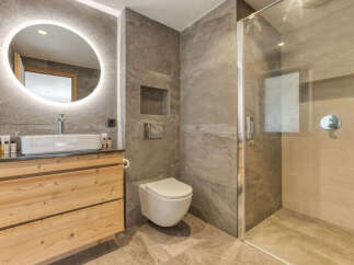 Experience modern luxury in this stunning bathroom, featuring a sleek vanity with a vessel sink and a large, illuminated round mirror.