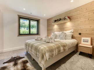 Experience cozy mountain living in this charming bedroom featuring a comfortable bed adorned with plush robes and towels.